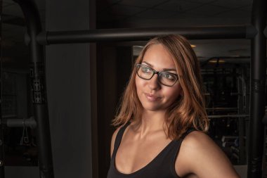 Kız fitness, güneş gözlüğü takıp yan tarafa bakıyor.