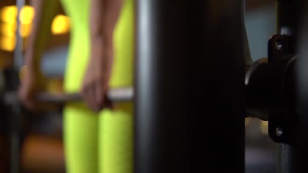 Chica adulta en el simulador Smith culturismo, levantamiento de pesas. Elevador, amarillo — Vídeo de stock