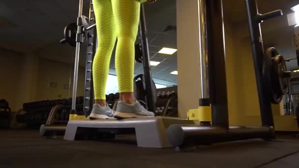 The girl athlete in the simulator Smith, training for weightlifting yellow — Stock Video