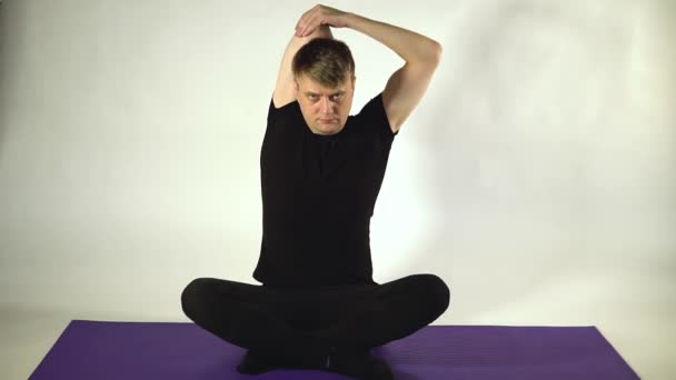 Guy táhne ruku za loket na bílém pozadí ve fitness na skupinových sezení — Stock video