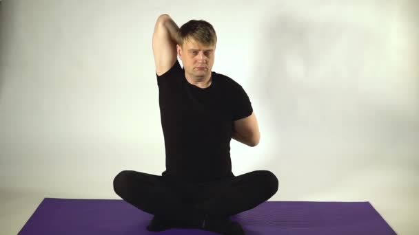 Lock achter zijn rug, stretching in fitness op een witte achtergrond een man trekt zijn armen uit met een blik van zijn gezicht — Stockvideo