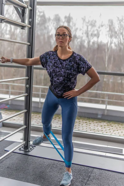 In a fitness club, a person does exercises with TRX is her strength