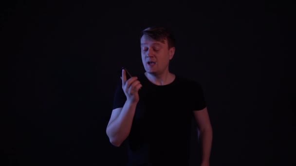 Der Mann verabschiedet sich am Telefon und läuft auf schwarzem Hintergrund — Stockvideo