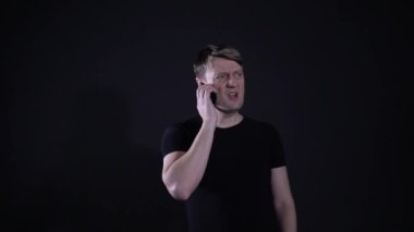 Adam siyah arka planda telefonla küfrediyor, bağırıyor.
