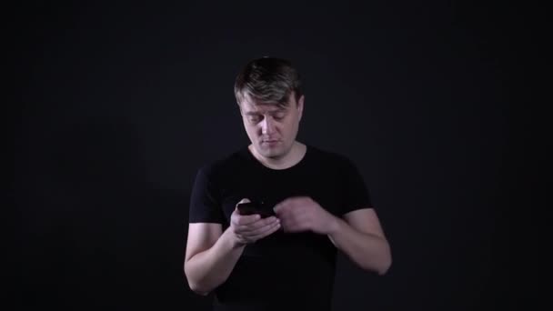 De vermoeide man veegt zweet van zijn voorhoofd op een zwarte achtergrond — Stockvideo