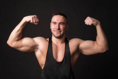 Siyah arka planda pazılarını gösteren genç bir adam.