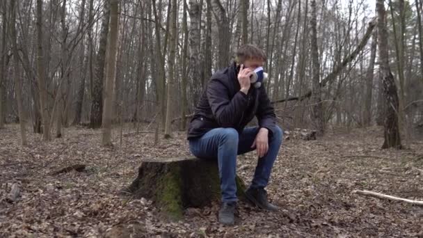 Человек в лесу covid19 в противогазе разговаривает по телефону — стоковое видео