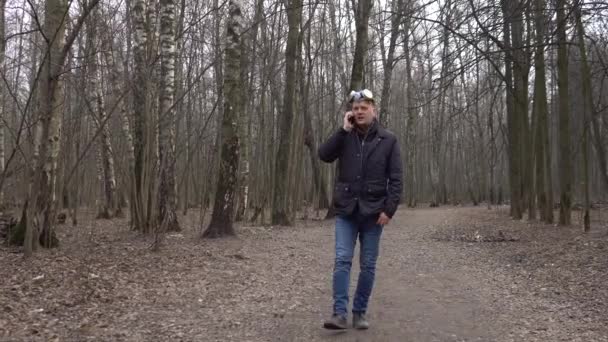 Covid19 met een gasmasker op zijn hoofd pratend aan de telefoon in het bos — Stockvideo