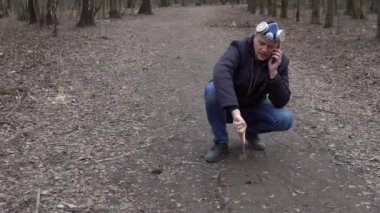 Maske yere bir çubuk ile yazıyor. Covid19 telefonda konuşuyor.