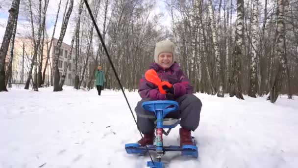 मुलगी हिवाळ्यात जंगलातून उरणला जाते आणि बर्फबॉल गोळा करते — स्टॉक व्हिडिओ