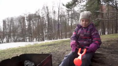 Ormanda ızgarası ve kartopu maşası olan bir kız.