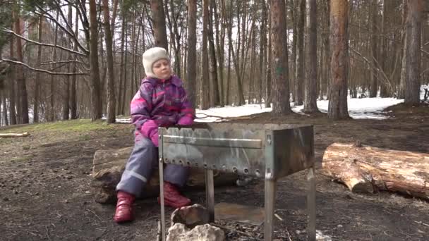 Fille assise près du gril sur le bord dans une forêt de pins — Video