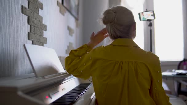 Piano online op het internet leert een meisje zelf-isolatie achter het virus covid19, leren piano vanaf een afstandsbediening telefoon, en een elektronische piano leraar. — Stockvideo