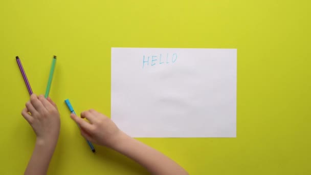 Girl writes on yellow background the word hello friends — Stock Video