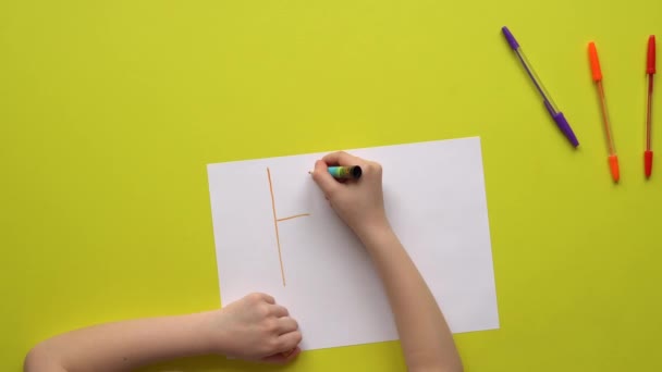 Yürüyen çocuk sarı tahtadan yapılmış bir masaya yardım yazısı yazıyor. — Stok video