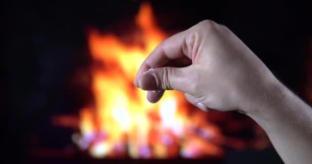 La sal se sienta una mano de hombre sobre el fondo de un hermoso fuego — Vídeos de Stock