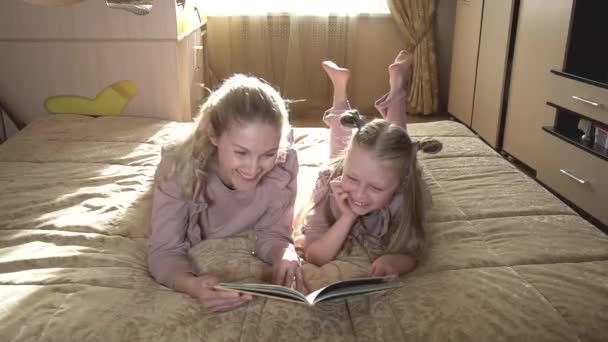 Η μαμά και η κόρη μου γελούν με το βιβλίο μαζί. Ευτυχισμένοι μαζί. Βλέπουν ένα βιβλίο.. — Αρχείο Βίντεο