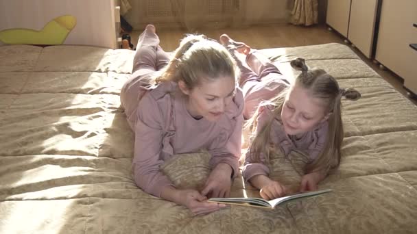 Las chicas leyeron el libro y felizmente lo discutieron. en la cama en una sala de luz . — Vídeos de Stock