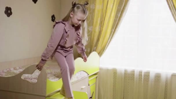 침대에 누운 채 기쁨으로 아이가 내려오고 행복 한 아이가 계단을 올라 노란 침대에서 내려갑니다.. — 비디오