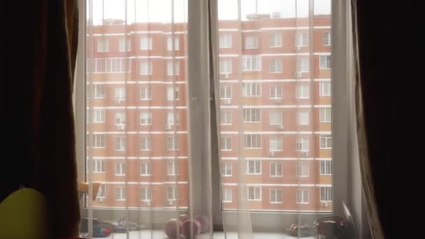 Ventana abierta, cortinas delgadas, con vistas a la casa de ladrillos rojos — Vídeos de Stock