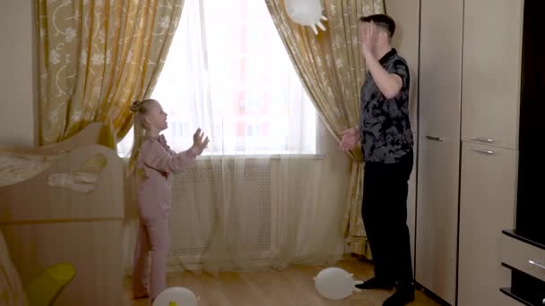 Genieten van jonge vader spelen handschoenballen met een mooi meisje aansteker in een grote woonkamer in modieuze kleding. Op tegen de wieg en bank. — Stockvideo