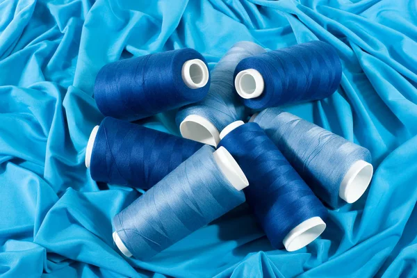 Голубые бобины ниток на голубой ткани — стоковое фото
