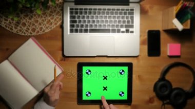 Bir çalışma alanı üzerinde yeşil bir ekran ile tablet pc kullanarak. Havadan görünümü