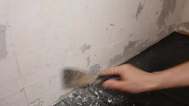 İşçi duvardan bir Spatula ile eski sıva kaldırır.