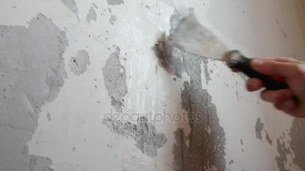 Рабочий снимает со стены старую штукатурку шпателем — стоковое видео