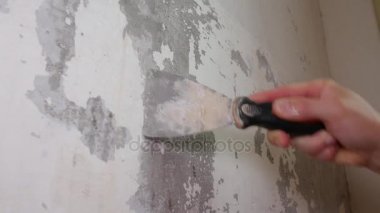 İşçi duvardan bir Spatula ile eski sıva kaldırır.
