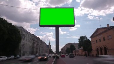 Yoğun bir cadde üzerinde yeşil bir ekran ile bir Billboard. Zaman atlamalı.