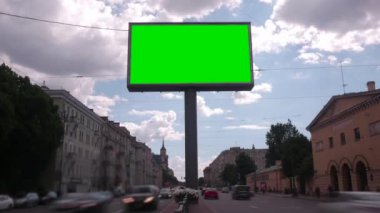 Yoğun bir cadde üzerinde yeşil bir ekran ile bir Billboard. Zaman atlamalı.