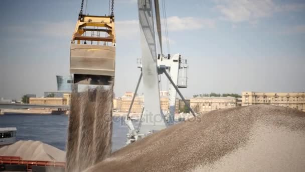 Nakládací jeřáby vypouštění drcený kámen z lodi na molo. — Stock video