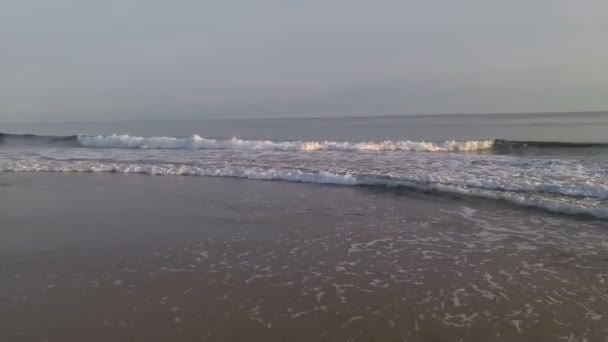 Vågorna kraschar försiktigt på en lugn sandstrand. Solnedgång — Stockvideo