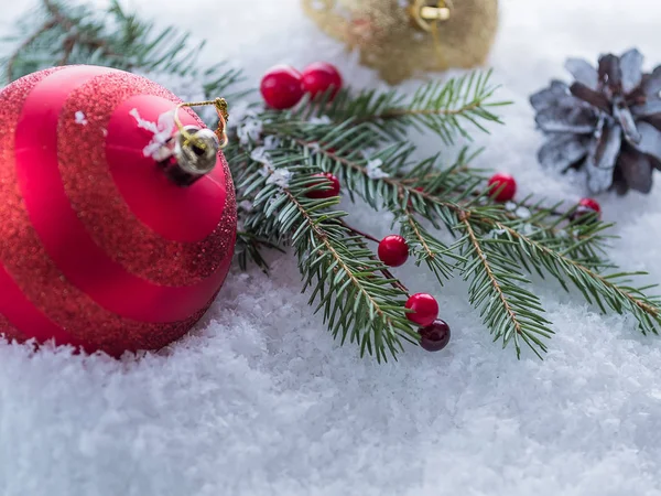 Christmas tree branch, red berries and  red ball on snow