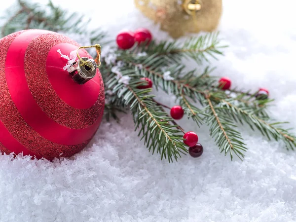 Vánoční větev, červené bobule a červený míč na sněhu — Stock fotografie