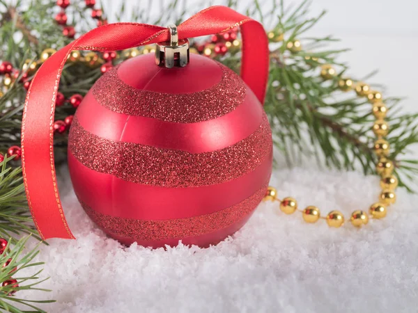 Boule de Noël rouge avec branches de sapin sur neige — Photo