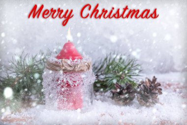 Bir mum, koni ve çam dalları ile Noel kartı. Kar yağışı ile