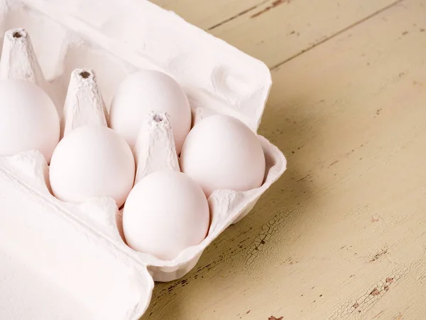 Embalagem aberta com ovos brancos em um velho fundo de madeira — Fotografia de Stock