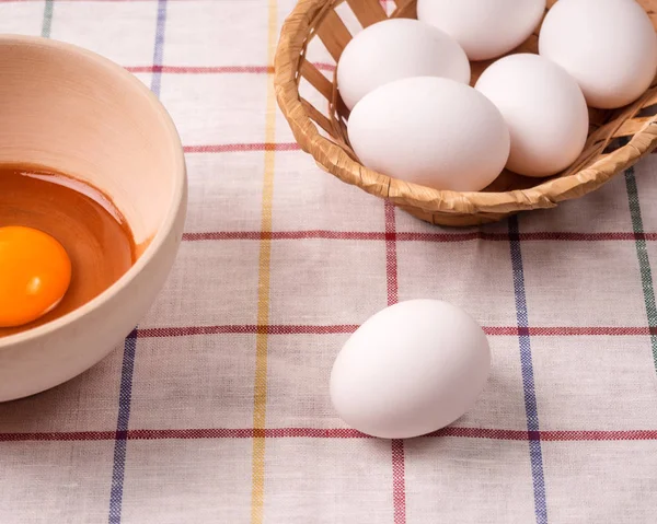 Fából készült tál tojás sárgáját, egy kosár tojással az asztalon. Főzés élelmiszer — Stock Fotó