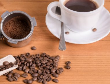 Kahve çekirdekleri, dağıtıcı ve kupa ahşap arka plan üzerinde