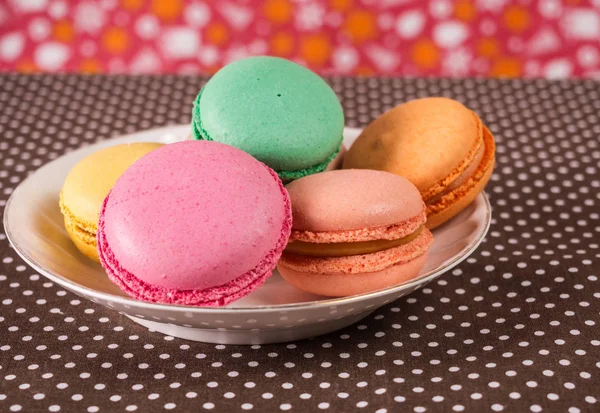 Macaroni francesi o italiani colorati impilano su piatto bianco messo sul tavolo — Foto Stock