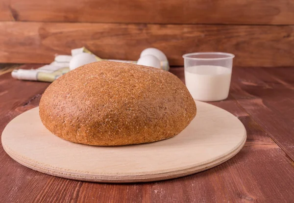 Grain round bread on a wooden board. — Stock Photo, Image