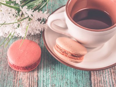 fincan çay ve bir sepet macaroons masada.