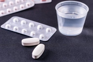 Tabletler ve su siyah bir arka plan ile plastik cam