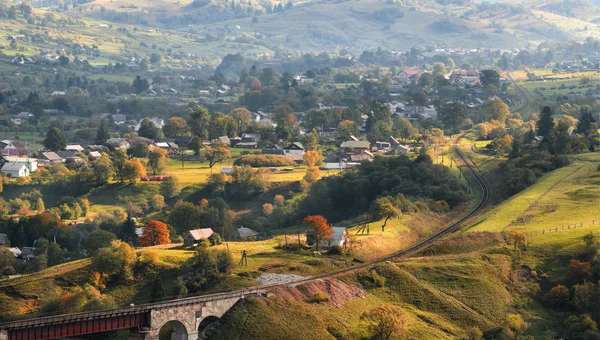 Sonbahar manzara bir demiryolu viyadük, dağlar ve dağların eteklerinde bulunan bir köy. Transcarpathia, Ukrayna ve Romanya sınırı. 
