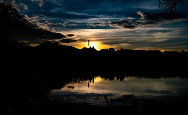 Siluet ağaçlarıyla gün batımı ve gölde yansıma