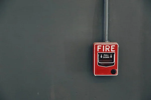 Bir kırmızı alarm çekme itfaiye koyu gri duvar.