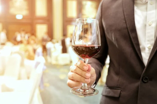 Bir iş adamı bir kadeh şarap ile ray sarı ışık içinde belgili tanımlık geçmiş şirket parti holding takım elbise giymiş, kapatın. Kavram ve iş başarısı, kutlama parti fikri.