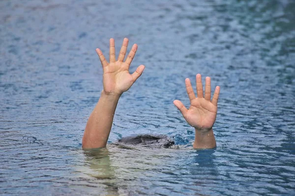 Man drowning in out door swimming pool while swimming alone, raising two hands and asking for help